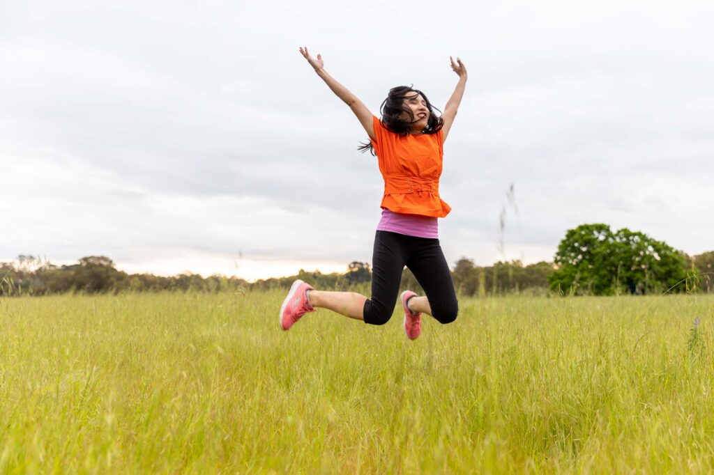 a woman jumping in the field full of joy