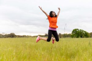 a woman jumping in the field full of joy